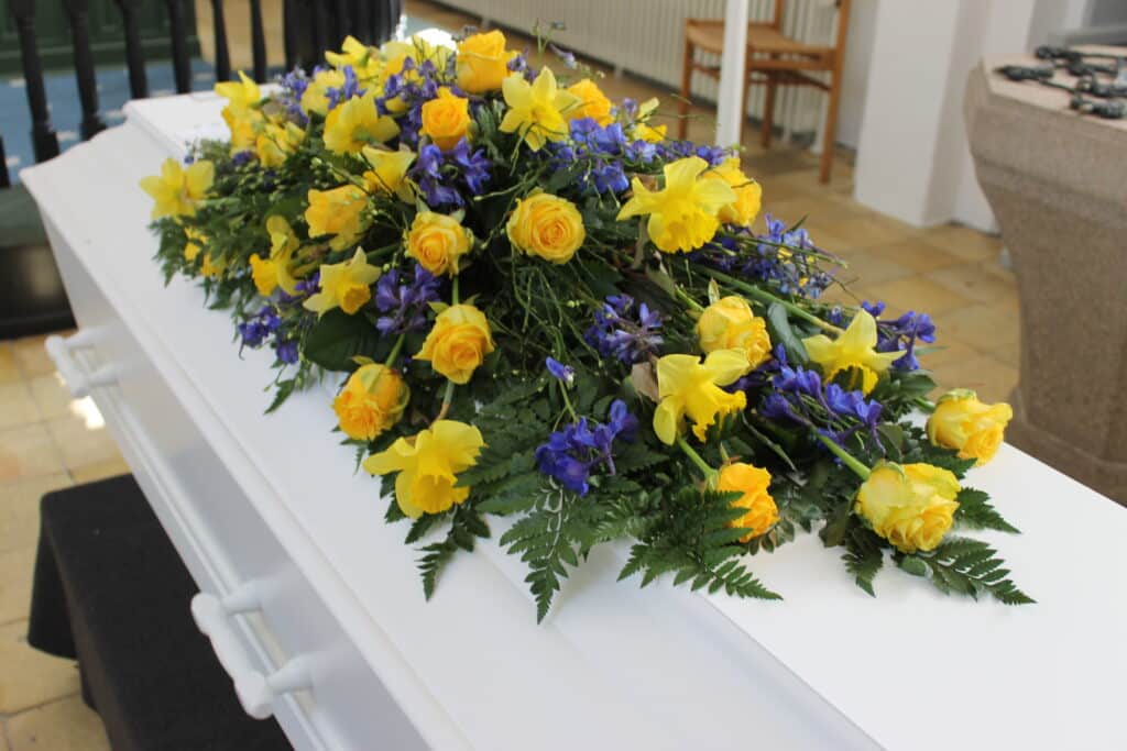 Kistepynt med gule roser, påskeliljer og blå blomster