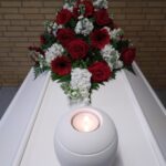 Tændt mindelys på kiste med røde roser i Hjallese Kirke