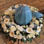 bedemand i Nr. Lyndelse urnebegravelse med blå urne i hvid blomsterkrans