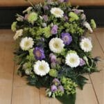 Blomsteropsats med hvide og lilla blomster ved Joan Holst begravelser