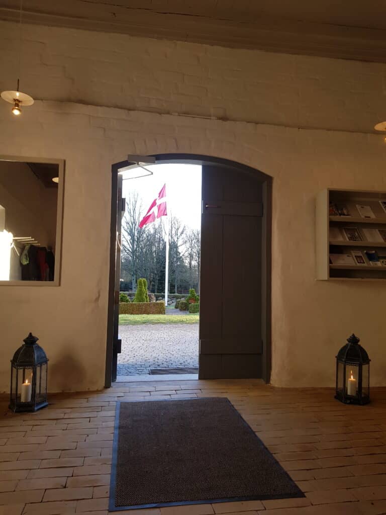Kig ud af døren i Sanderum Kirke på flag på halv ved bisættelse