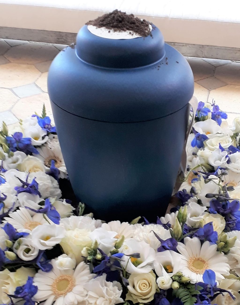 Blå urne i blå og hvid blomsterkrans til urnebegravelse