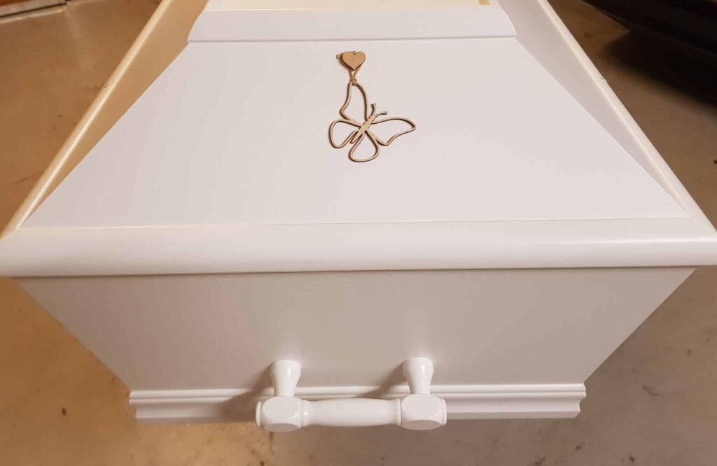 Kisten pyntet med sommerfuglevedhæng ved begravelse