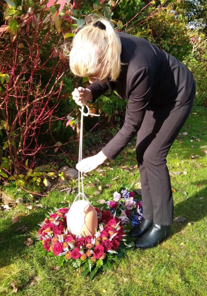 En bedemands opgave nedsænke en urne gennem en blomsterkrans